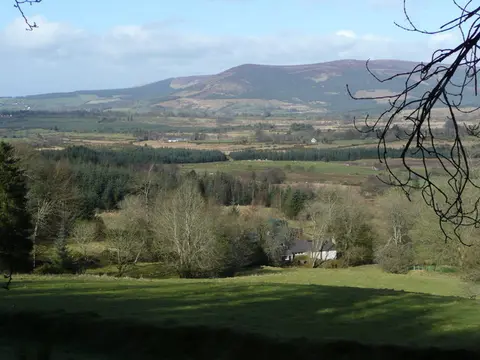Glen of Imail A fine view over wooded countryside in western County Wicklow. Sugarloaf and Lobawn are the hills ranged in the distance. In the foreground is Ballinabarney Farm.