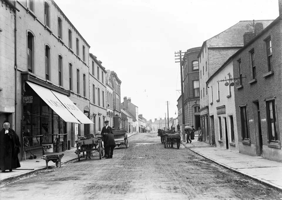 In typically infuriating fashion, the car registration number is partly obscured by the the two gents having a chat, but 3844 is visible. Date: 1910?? NLI Ref.: Eas 2728