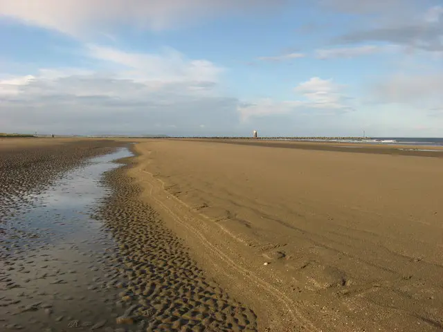 Mornington Strand, Co. Meath Sand banks exposed on a wide strand at low tide. The training walls at mouth of the River Boyne are visible in the distance.