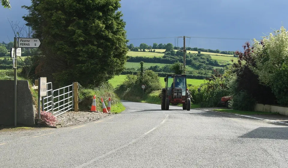 IHC Tractor approaching the hamlet of The Harrow, near to Myaugh, Glen Village, Boleyvogue and Tinnacross Cross Roads, County Wexford, Ireland.