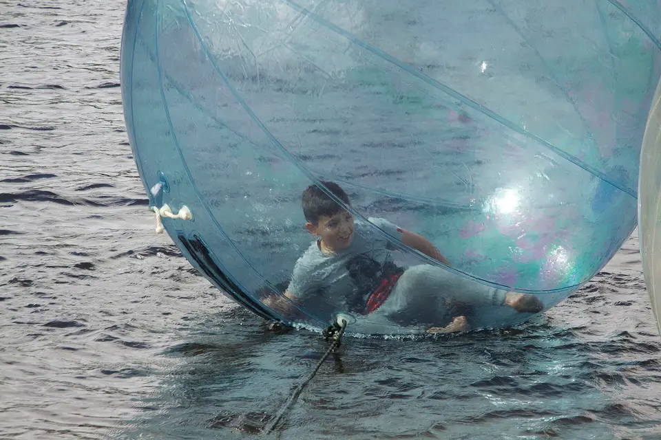 Kid rolling in an inflatable plastic ball (Water ball) on river Shannon in Roosky (Ireland)