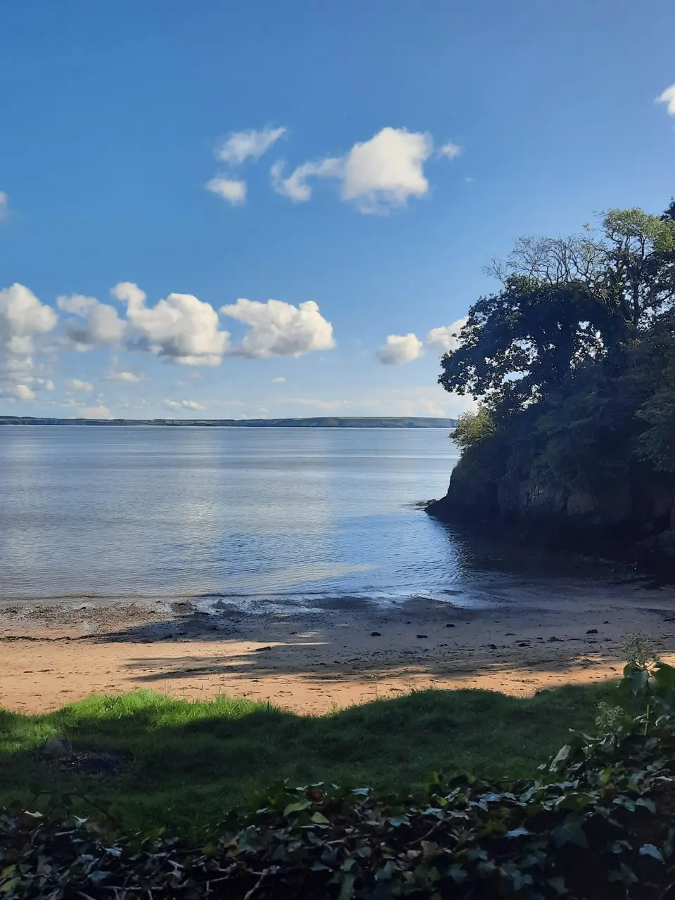 A private beach with a view of the sea near a small cliff on a clear sunny day.